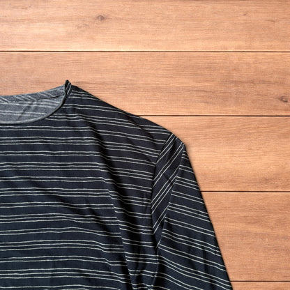 Relaxed fit navy and beige striped long sleeve top t-shirt laid flat on wooden surface showing front and back views.