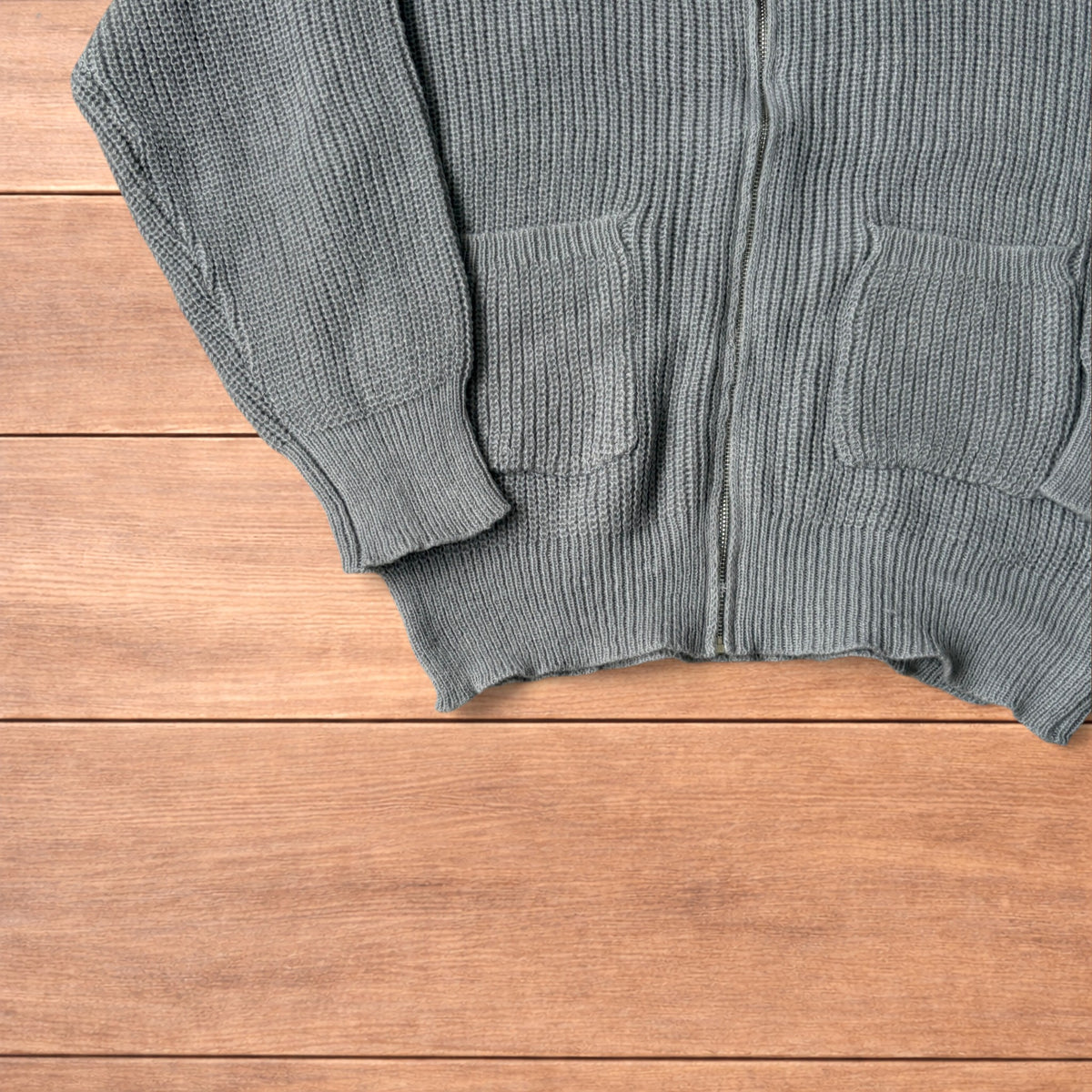 Grey Korean style knitted cardigan jumper with full zip and front pockets laid flat on wooden surface