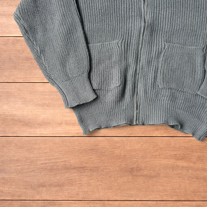 Grey Korean style knitted cardigan jumper with full zip and front pockets laid flat on wooden surface