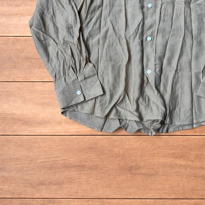 Vintage style camel beige button up long sleeve shirt with light blue buttons and chest pocket laid flat on wooden surface.