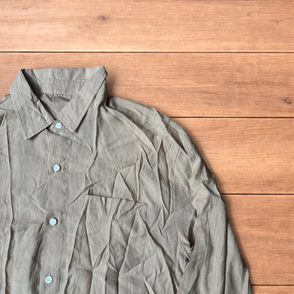 Vintage style camel beige button up long sleeve shirt with light blue buttons and chest pocket laid flat on wooden surface.