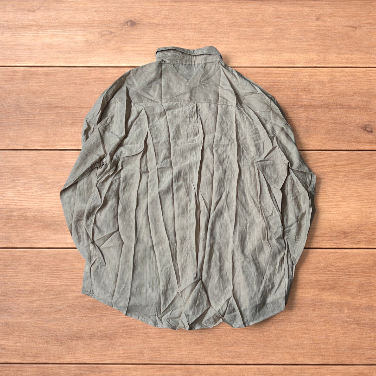 Vintage style camel beige button up long sleeve shirt with light blue buttons and chest pocket laid flat on wooden surface.