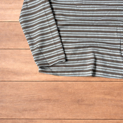 Relaxed fit striped knit top t-shirt in brown and cream laid flat on wooden floor.