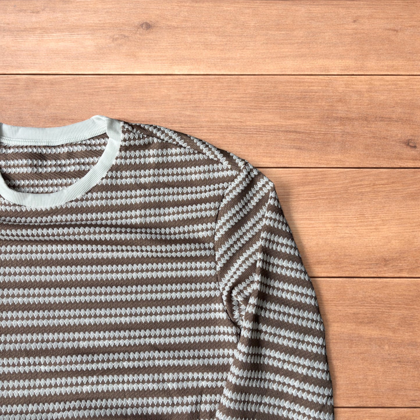 Relaxed fit striped knit top t-shirt in brown and cream laid flat on wooden floor.
