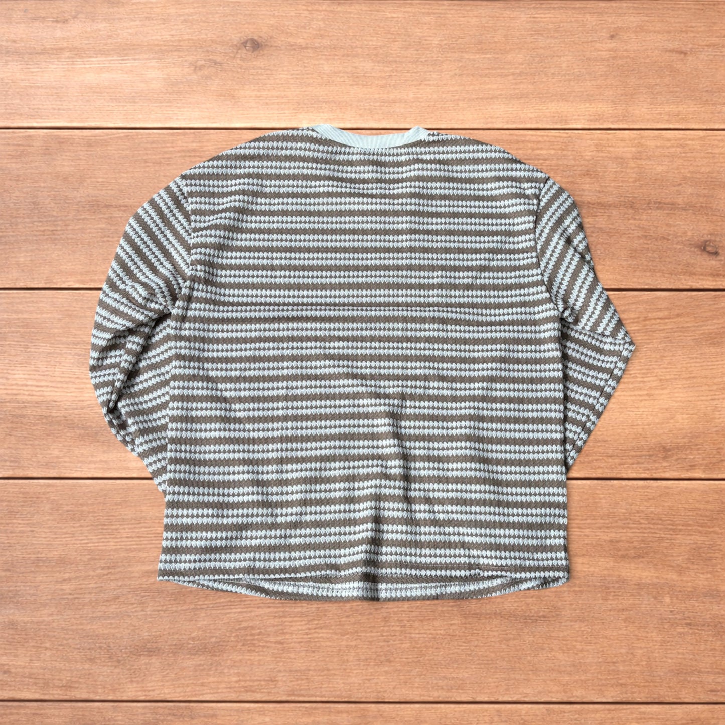 Relaxed fit striped knit top t-shirt in brown and cream laid flat on wooden floor.