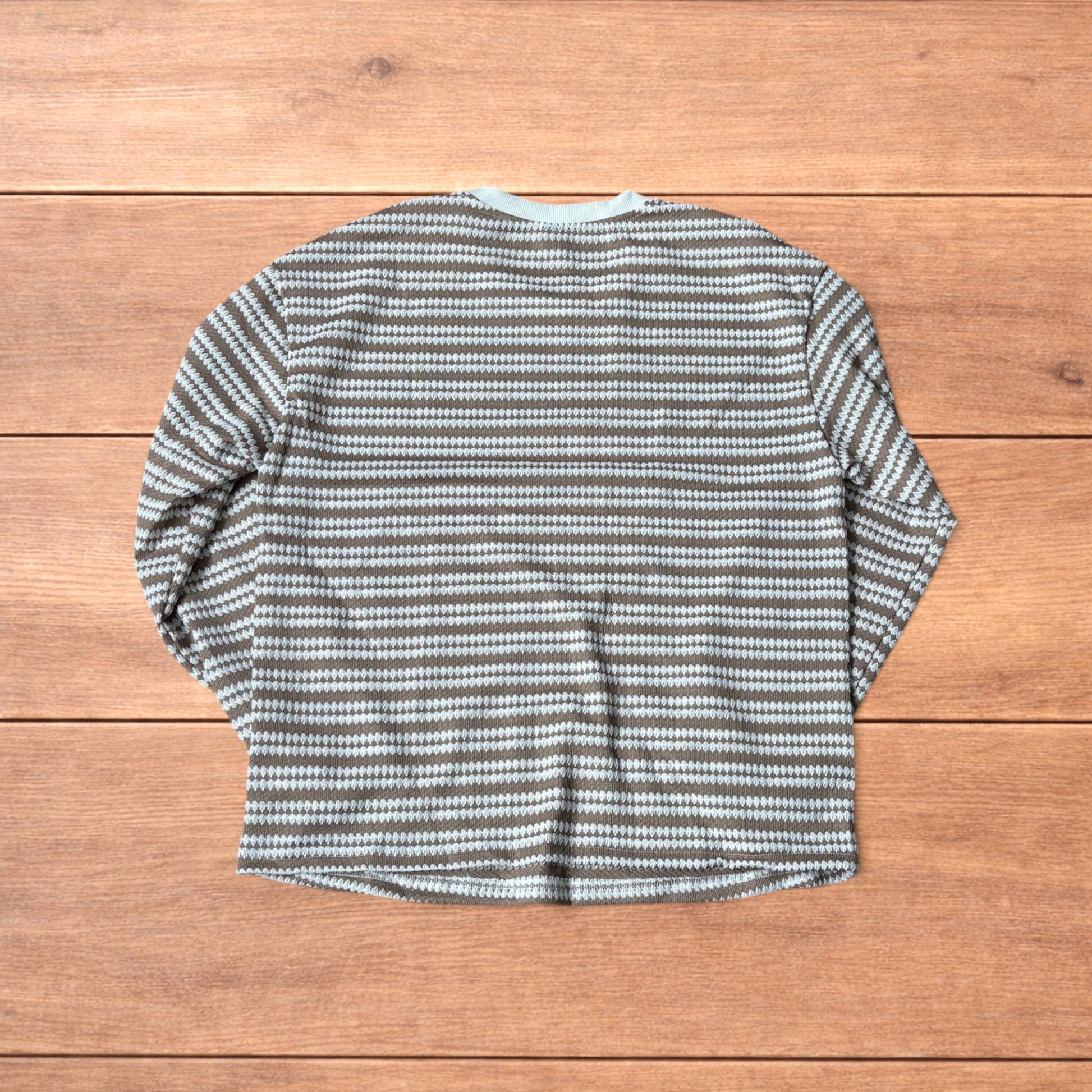 Relaxed fit striped knit top t-shirt in brown and cream laid flat on wooden floor.