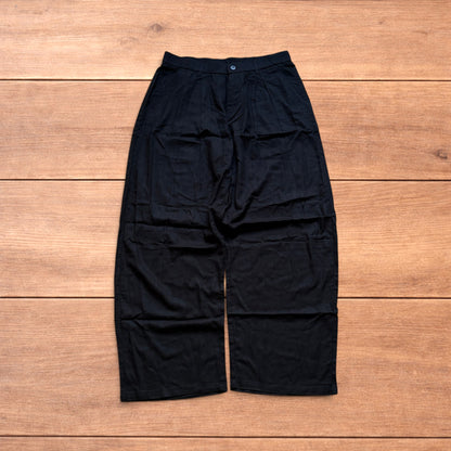 Vintage linen style black baggy wide leg trousers laid flat on wooden background.