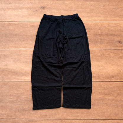 Vintage linen style black baggy wide leg trousers laid flat on wooden background.