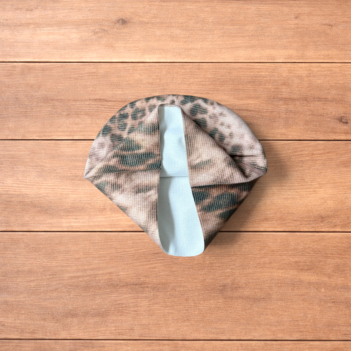 Japanese vintage style beige beanie hat with beige animal print pattern laid flat on wooden surface.