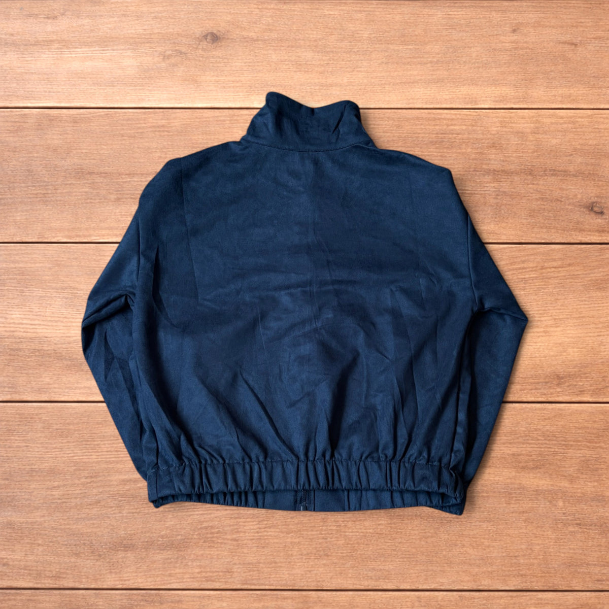 Japanese style navy blue zip up track jacket with white knotted fastenings on wooden background.