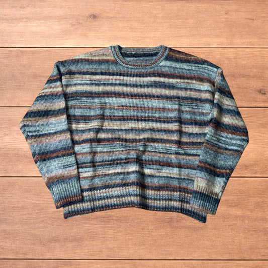 Vintage style striped knitted sweater jumper laid flat on a wooden surface featuring blue and beige marl stripes.