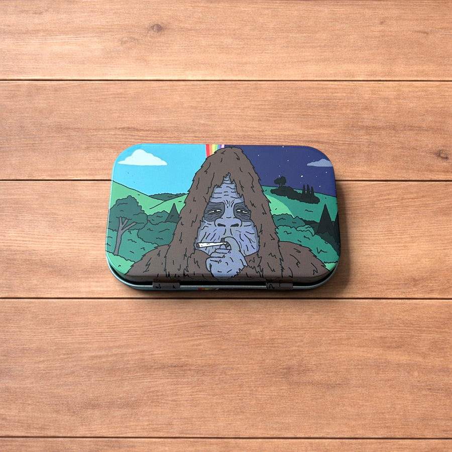 The Big Lez Show Sassy Sasquatch storage tin box showing detailed character artwork on a wooden surface.