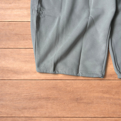Pale grey baggy joggers laid flat showing elastic waistband with drawstring and wide leg cut.