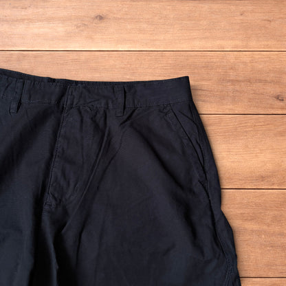 Black baggy balloon chinos laid flat on wooden surface showing wide balloon leg and elasticated hems.