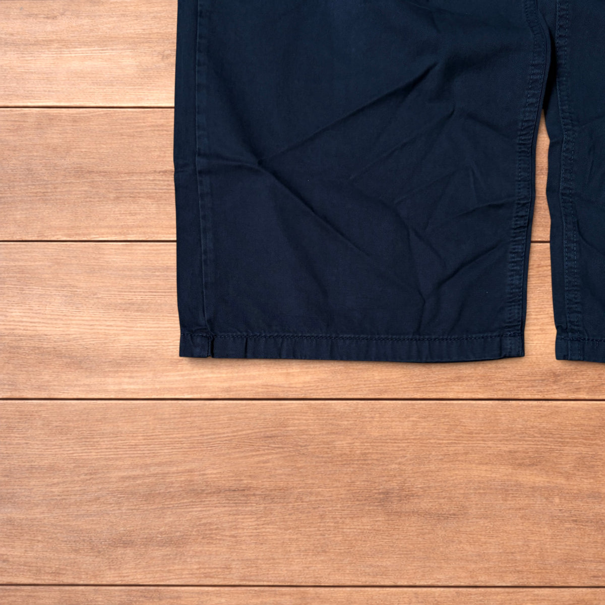 Navy blue baggy chinos laid flat showing elasticated waistband and wide leg cut.