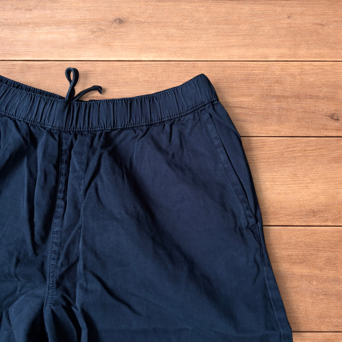 Navy blue baggy chinos laid flat showing elasticated waistband and wide leg cut.
