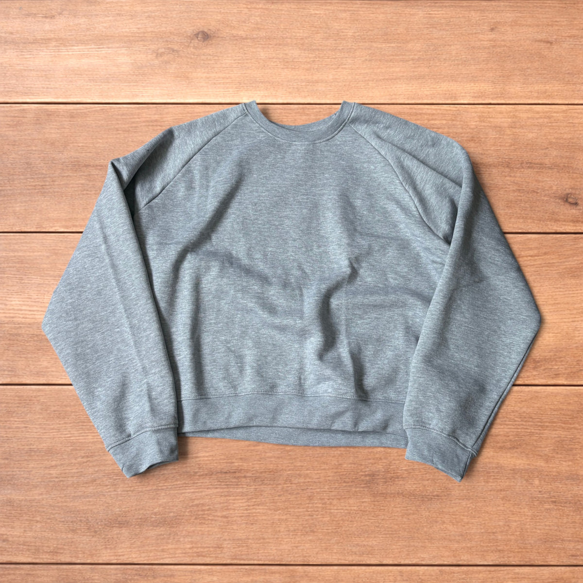 Grey baggy gym sweatshirt laid flat showing front, raglan sleeves, ribbed neckline, cuffs, and hem.