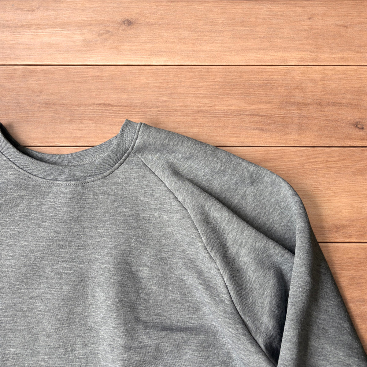 Grey baggy gym sweatshirt laid flat showing front, raglan sleeves, ribbed neckline, cuffs, and hem.