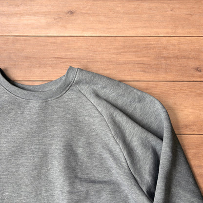 Grey baggy gym sweatshirt laid flat showing front, raglan sleeves, ribbed neckline, cuffs, and hem.