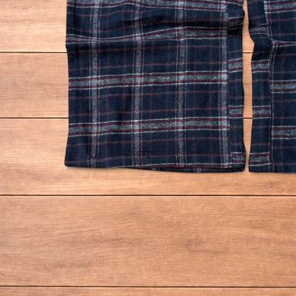 Navy and burgundy plaid baggy loungewear trousers with elasticated waistband and wide legs laid flat on wood surface.