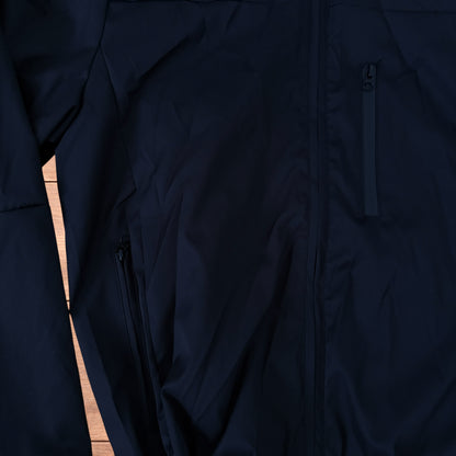 Black outdoor windbreaker jacket with hood, zip pockets and toggled hem laid flat on wooden surface.