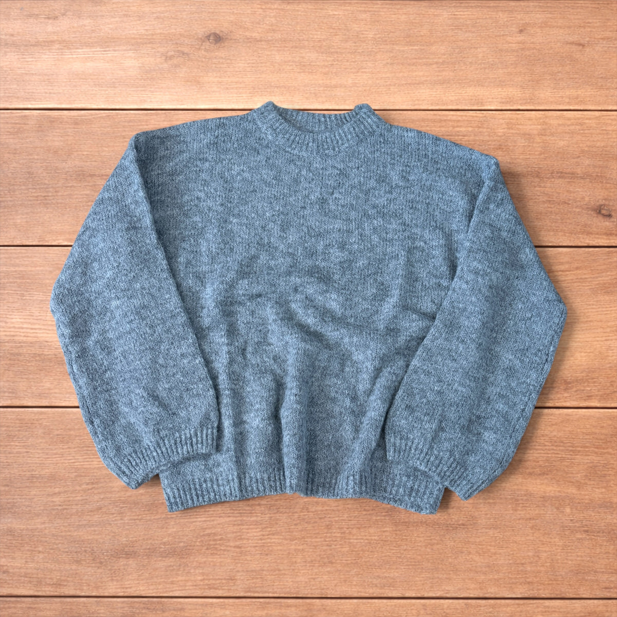 Vintage style knitted grey sweater jumper laid flat showing ribbed cuffs and relaxed fit.
