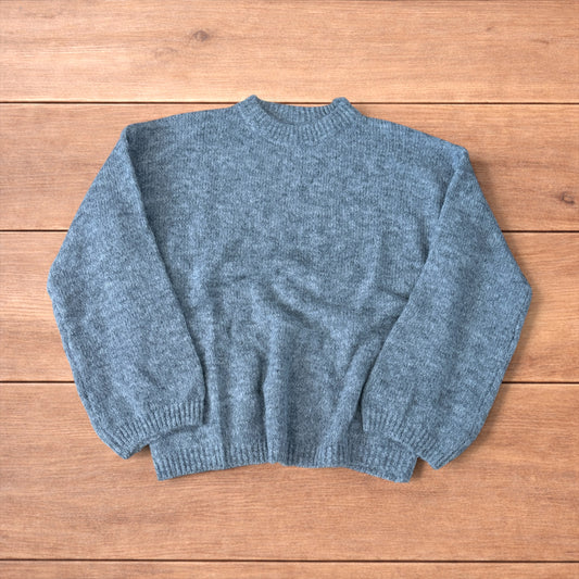 Vintage style knitted grey sweater jumper laid flat showing ribbed cuffs and relaxed fit.