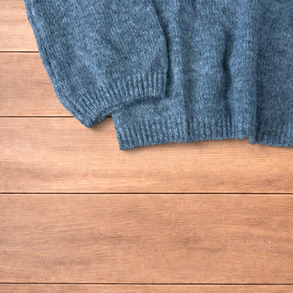 Vintage style knitted grey sweater jumper laid flat showing ribbed cuffs and relaxed fit.