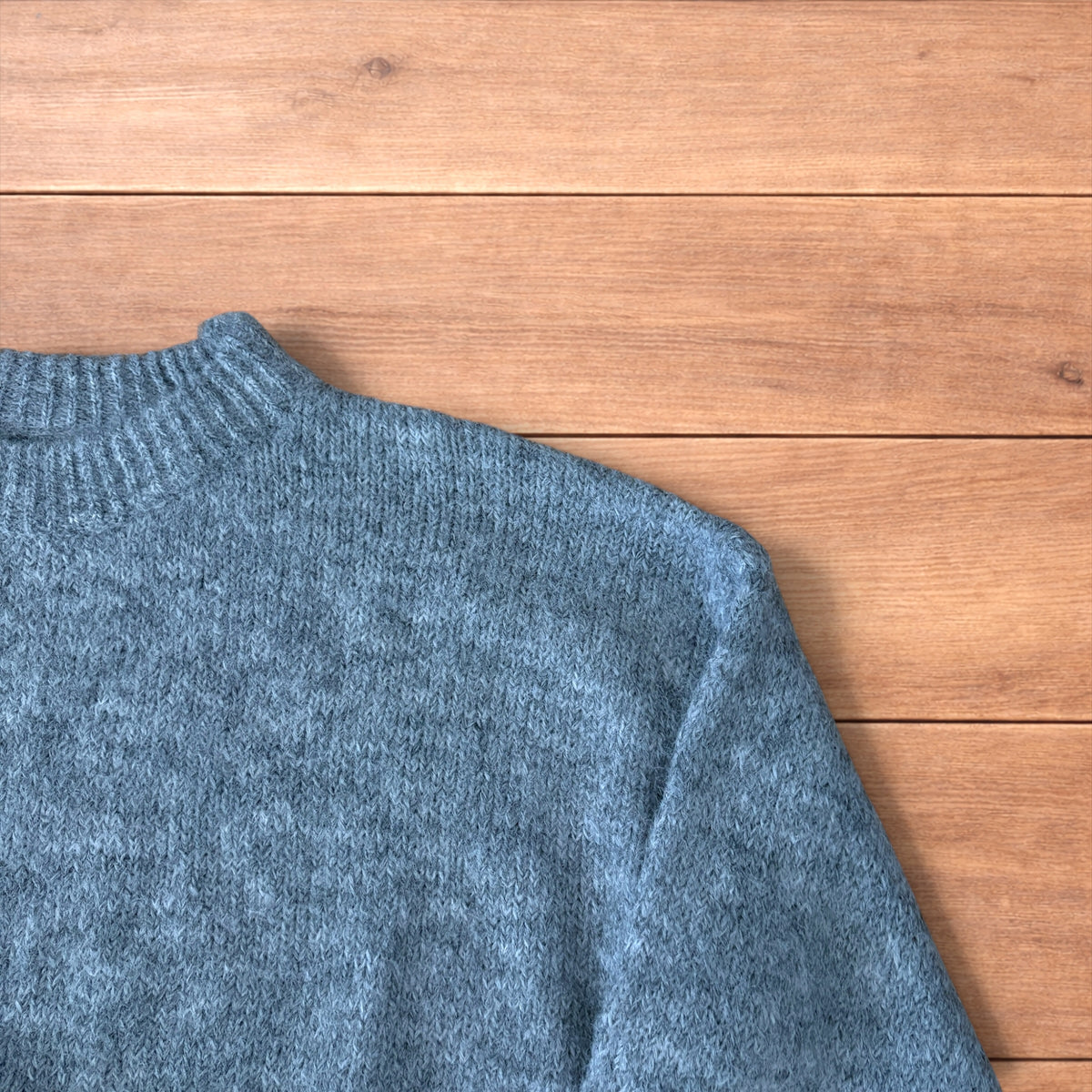 Vintage style knitted grey sweater jumper laid flat showing ribbed cuffs and relaxed fit.