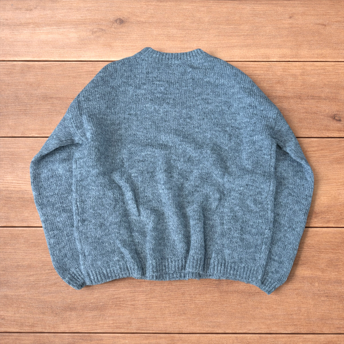 Vintage style knitted grey sweater jumper laid flat showing ribbed cuffs and relaxed fit.