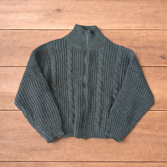 Dark green vintage style knitted cardigan jumper with cable knit pattern and full zip collar laid flat on wooden background.
