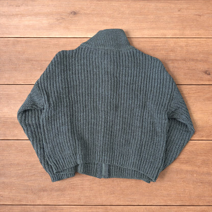Dark green vintage style knitted cardigan jumper with cable knit pattern and full zip collar laid flat on wooden background.