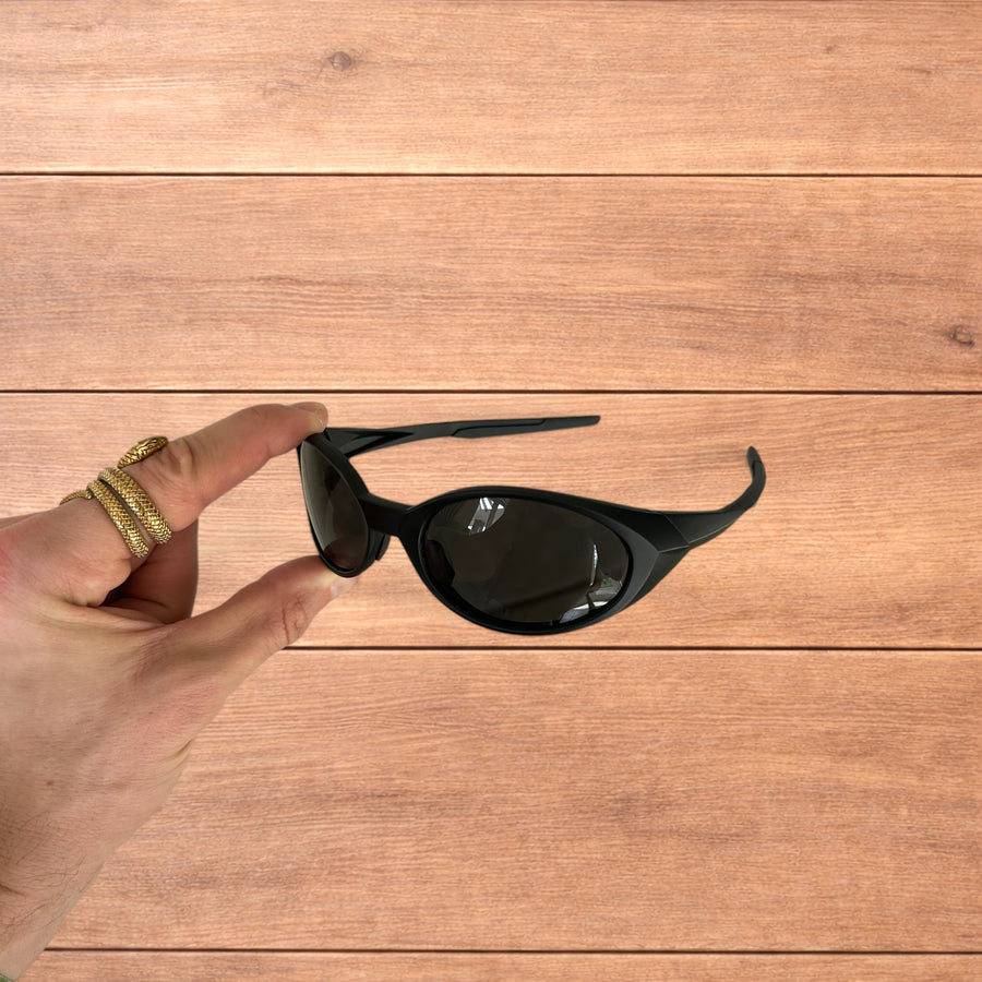 Insane mirrored polarised sunglasses in black with black lens held in hand over wooden background