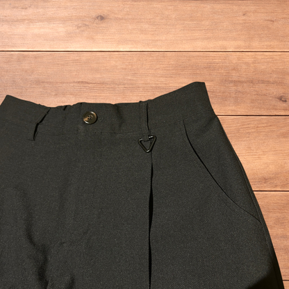 Black baggy wide leg tailored trousers with pleats and white stitch detail, laid flat on wood surface