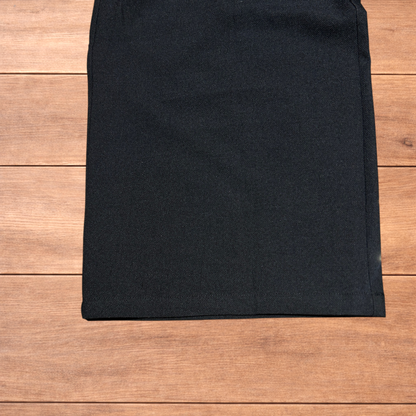 Black baggy wide leg tailored trousers with pleats and white stitch detail, laid flat on wood surface
