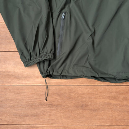 Khaki green lightweight shell anorak jacket with quarter zip and hood laid flat on wood surface.