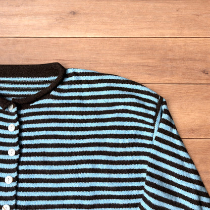 Turquoise and black striped vintage knitted cardigan jumper with button-up front laid flat on wooden surface.