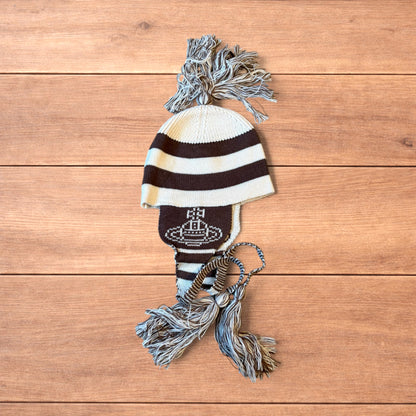 Vintage style striped dappy bobble hat with ear flaps and tassels in brown and cream laid flat on wooden surface.