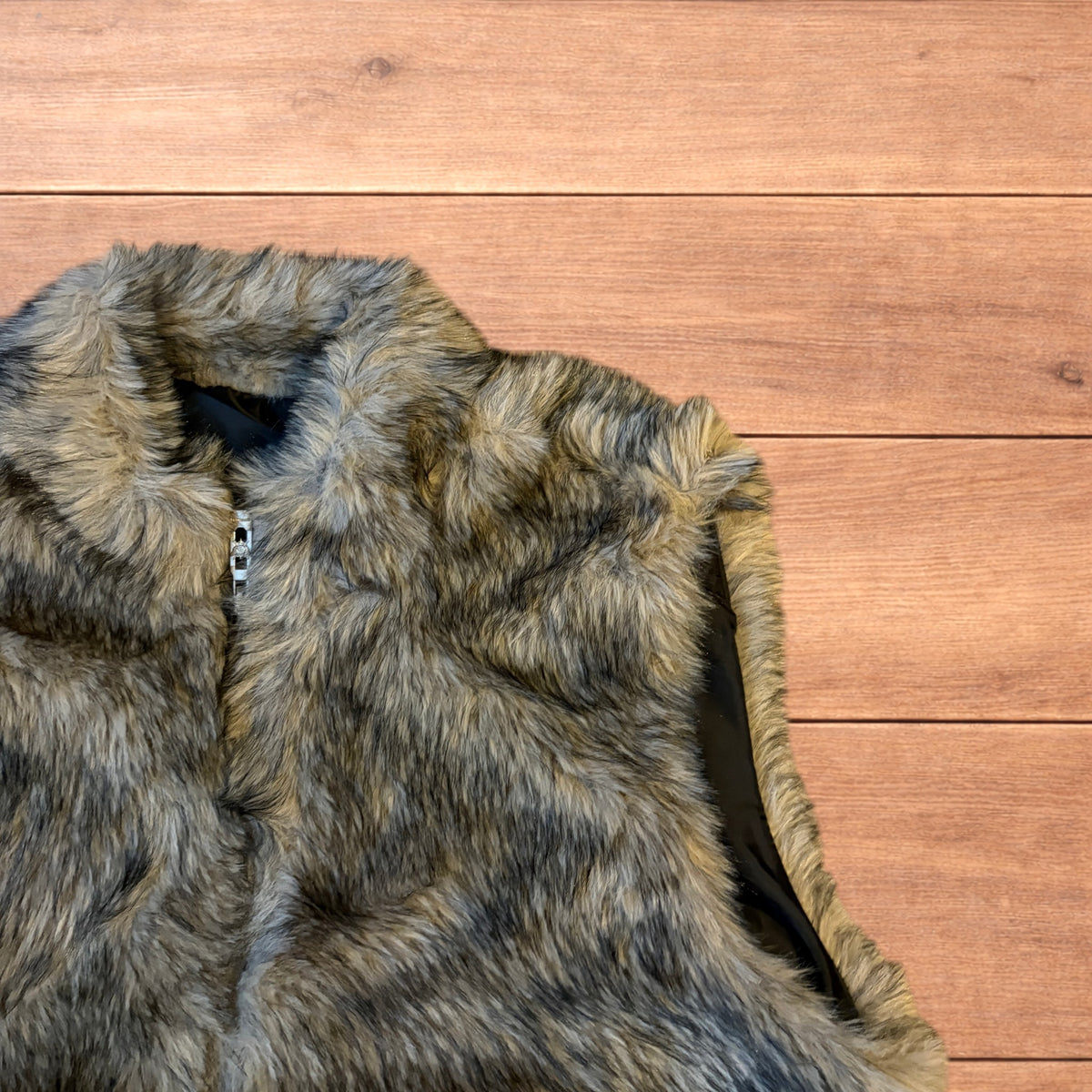 Beige brown faux fur gilet jacket with full zip on wooden surface