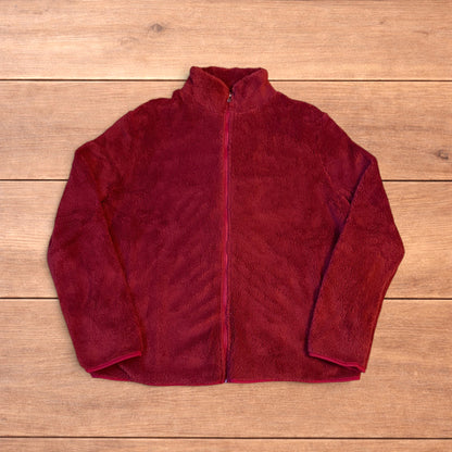 Deep dark red fluffy fleece zip up jacket laid flat on wooden surface.