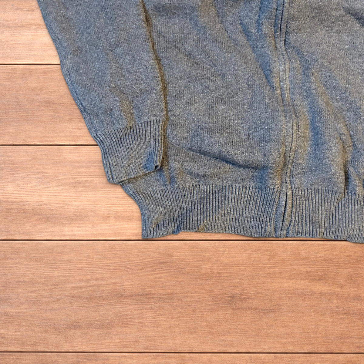 Grey vintage style knit track jacket with full zip and high neck laid flat on wooden surface.