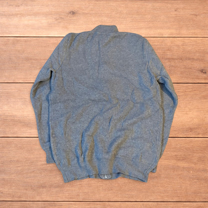 Grey vintage style knit track jacket with full zip and high neck laid flat on wooden surface.