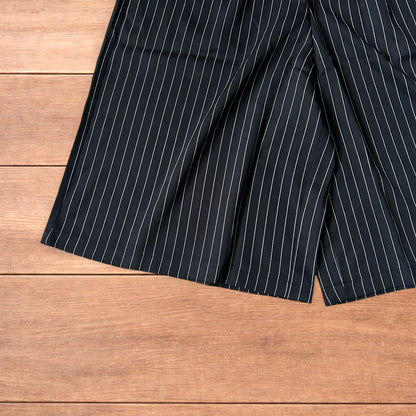 Black vintage style baggy wide long tailored shorts with white pinstripes laid flat on wooden surface