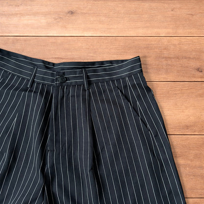 Black vintage style baggy wide long tailored shorts with white pinstripes laid flat on wooden surface
