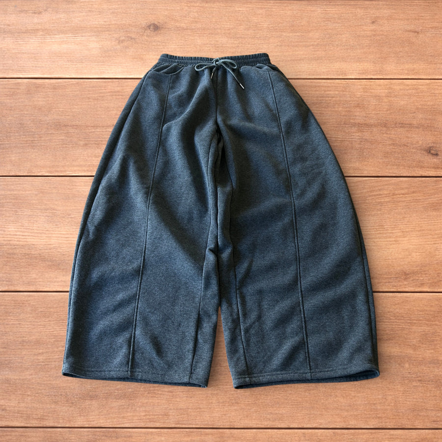 Dark grey super baggy wide leg Korean joggers with drawstring waist and front and back pockets laid flat on wooden floor.