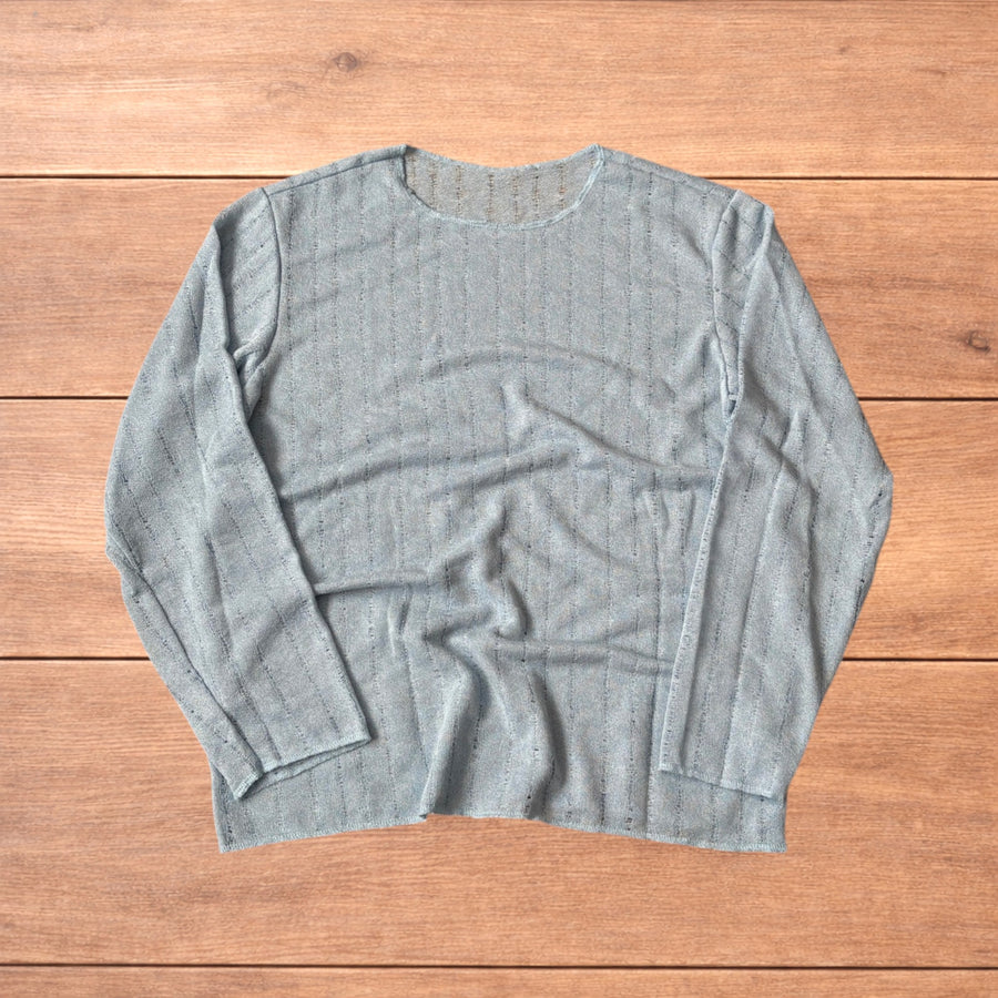 Light blue baggy long sleeve knit surfer style top laid flat on wooden surface