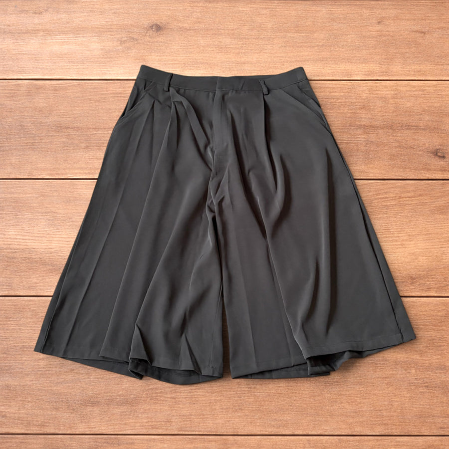Super baggy wide leg tailored black shorts jorts laid flat on wooden surface showing front, back and pocket details.
