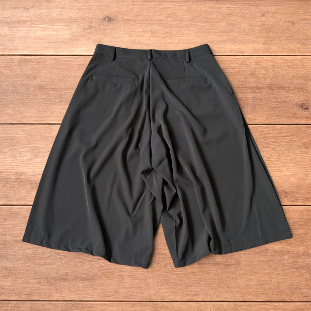 Back view of black baggy wide leg tailored three-quarter shorts