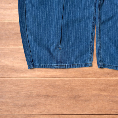 Vintage mid blue pinstripe baggy wide leg jeans with pleats laid flat on wooden surface