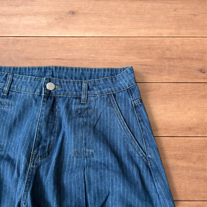 Vintage mid blue pinstripe baggy wide leg jeans with pleats laid flat on wooden surface